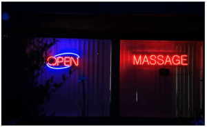 Neon signs for massage therapy in a shop window at night